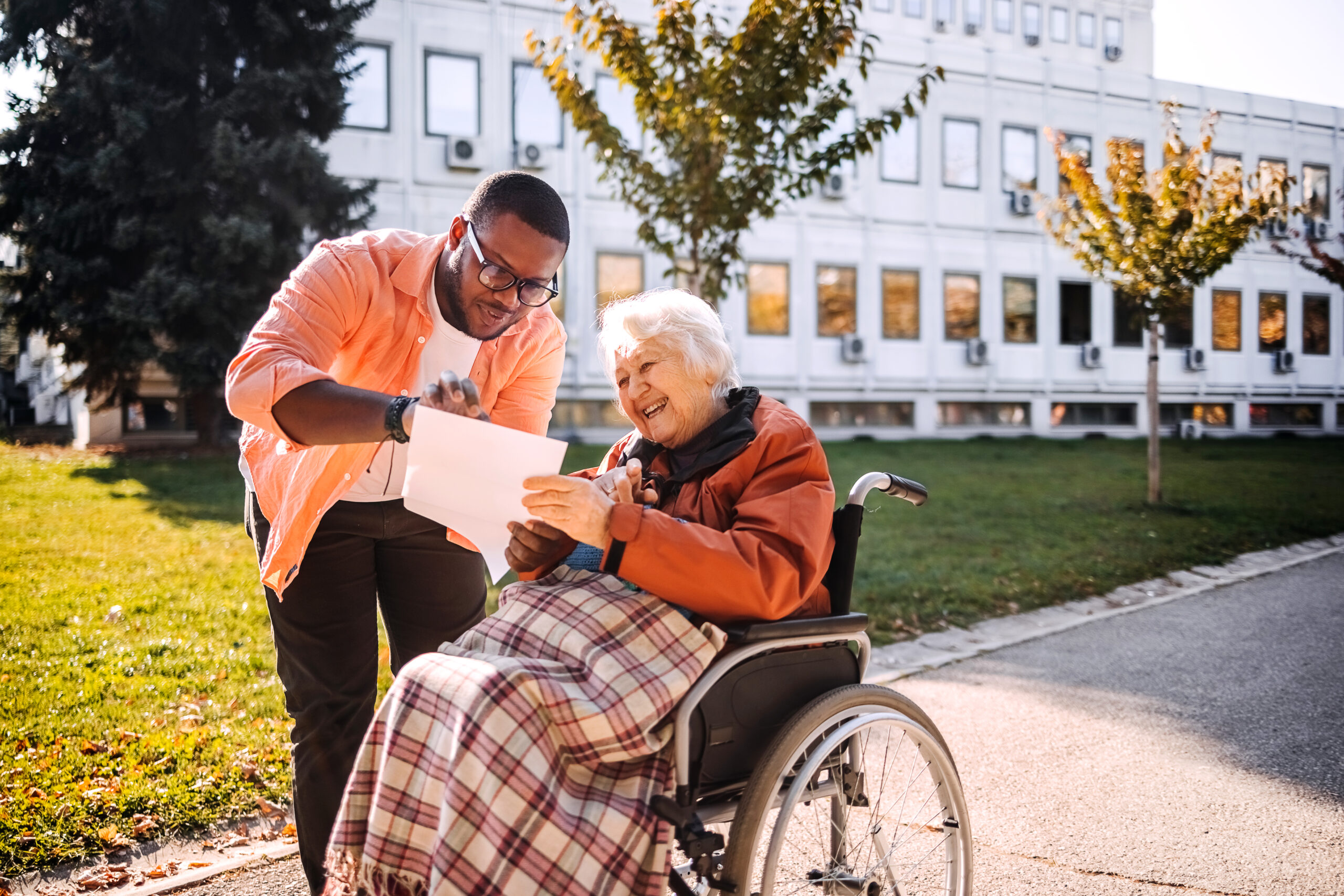 Spending time with older woman with disability outdoor in public park on sunny day in Autumn looking at recipe